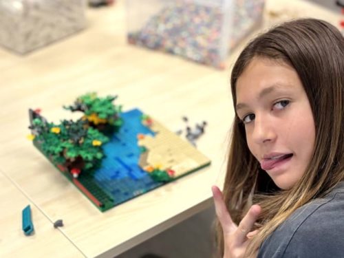 Une adolescente souriante participe à un atelier de construction dans l'espace créatif Ludi Briques.