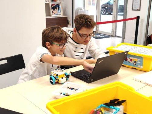 Deux enfants programment un robot en briques sur un ordinateur lors d'un atelier robotique Ludi Briques.