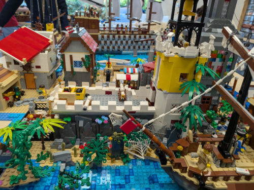 stage vacances lego mettant en scène un grand port historique, un fort côtier fortifié et des navires détaillés en briques.