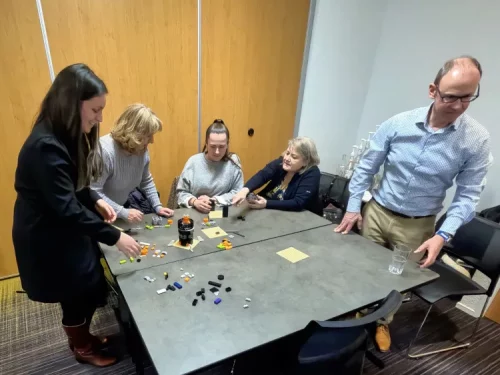 Petit groupe de collaboratrices et collaborateurs échangeant dans la bonne humeur lors d'une activité ludique d'entreprise à Strasbourg.