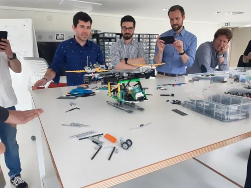 Équipe de collègues très concentrés assemblant un hélicoptère en briques lors d'une activité team building LEGO à Bordeaux.