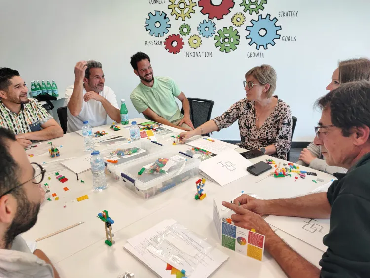 Équipe de collaborateurs souriante participant à une activité team building LEGO pour développer l'innovation en entreprise à Paris.