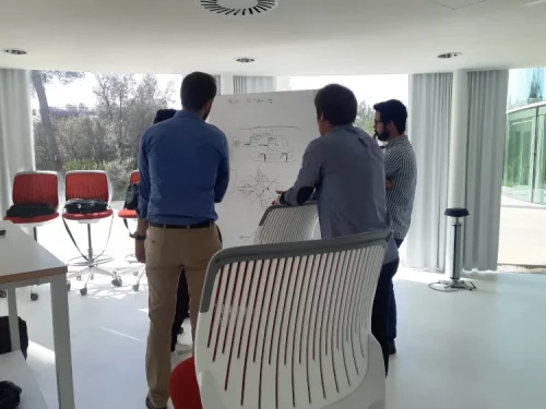 Collaborateurs dessinant les plans d'un hélicoptère sur un tableau blanc avant un atelier collaboratif de séminaire à Toulouse.