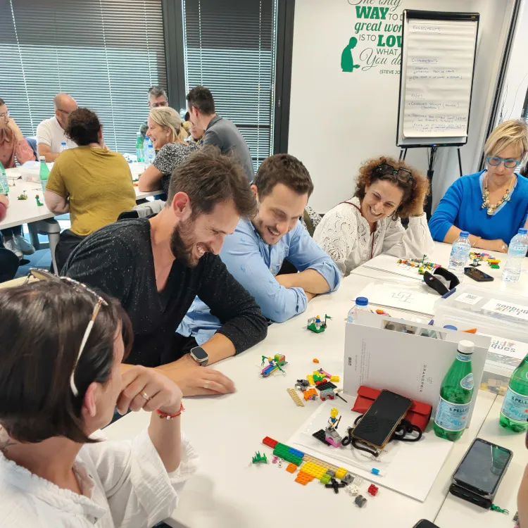 Équipe de collaborateurs riant aux éclats pendant une activité de team building original avec des LEGO à Bordeaux.