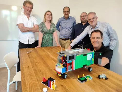 Équipe d'entreprise fière de présenter son camion construit en briques lors d'un team building original à Nantes.